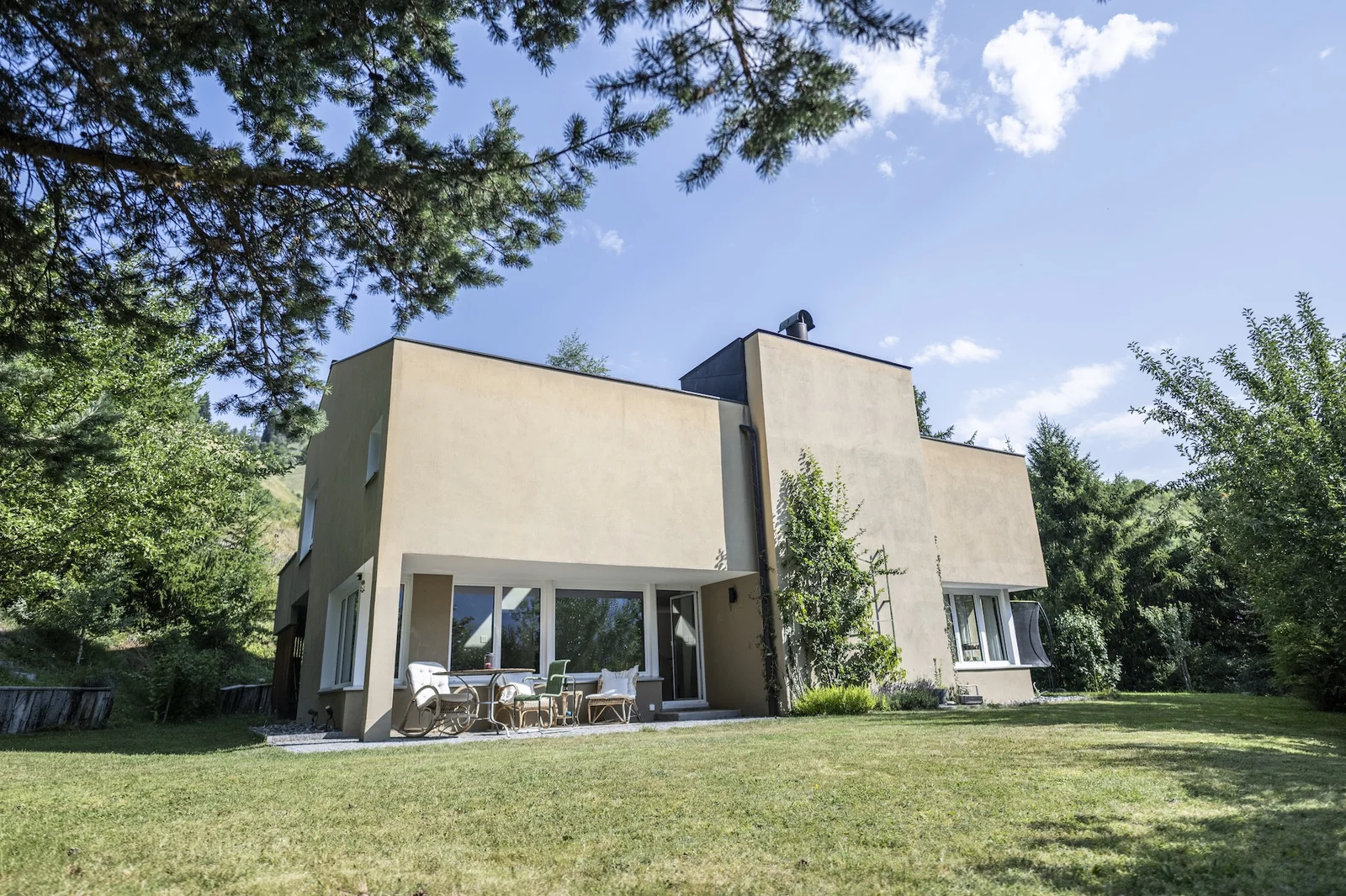 Klare Architektur der Chasa Val 17, umgeben von Bäumen und Garten